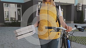 Close up of handsome man open door to a pizza delivery woman wearing yellow thermal backpack on a bike and recieves