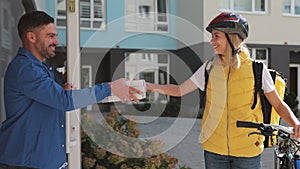 Close up of handsome man open door to a pizza delivery woman wearing yellow thermal backpack on a bike and recieves