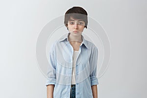 Close up of handsome masculine girl with trendy short haircut in casual clothes looking in camera with serious and calm