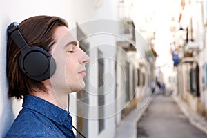 Close up handsome meditative man with headphones on city street