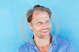 Close up handsome older man smiling against blue wall