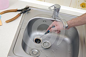 Close-up of handsome plumber hands repairing drain of kitchen sink