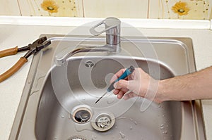 Close-up of handsome plumber hands repairing drain of kitchen sink