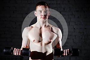 Close-up of handsome power athletic man training pumping up muscles with dumbbells.