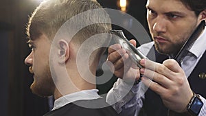 Close up of a handsome professioanl barber stylign hair of a man