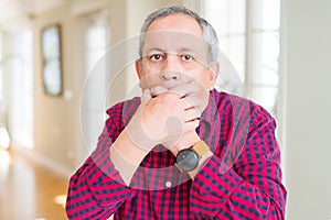 Close up of handsome senior man at home shocked covering mouth with hands for mistake