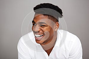 Close up handsome young african american man laughing and looking away against gray background