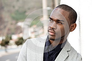 Close up handsome young african american man leaning against wall outside