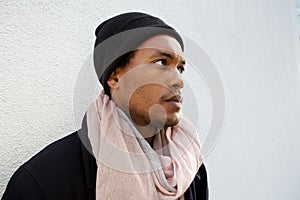 Close up handsome young african american man with winter jacket, beanie and scarf by white wall