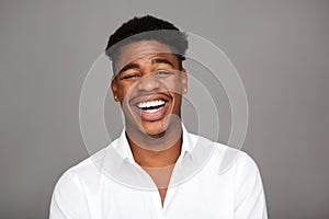 Close up handsome young black man laughing against gray background