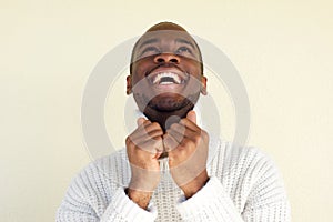 Close up handsome young black man laughing with sweater and looking up