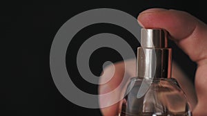 Close up of handsome young business man using perfume or deodorant on black background macro