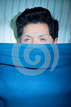 Close up of a handsome young man in bed with eyes opened suffering insomnia and sleep disorder thinking about his