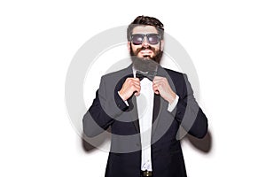 Close-up of handsome young man wearing sunglasses adjusting his bow tie and looking at camera