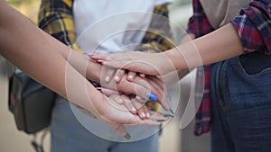 Close-up handstack of teenage Caucasian female hands outdoors. Unrecognizable group of girls stacking hands standing on