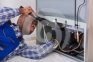 Handyman Checking Refrigerator With Flashlight