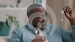 Close-up happy adult african american man sitting looking at camera showing bunch of keys from new purchased or rented