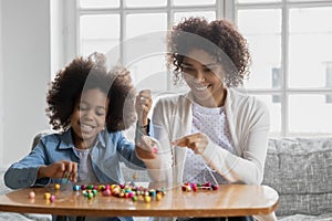 Close up happy African American mother and daughter crafting bracelets