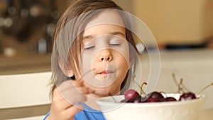 close-up happy baby girl eating ripe fresh cherries