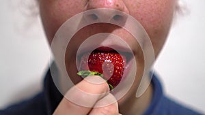 Close up happy beautiful young woman eating strawberry at home