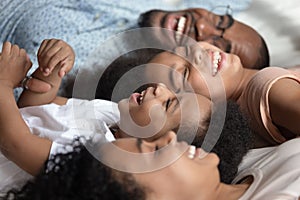 Close up of happy black family relax on bed together