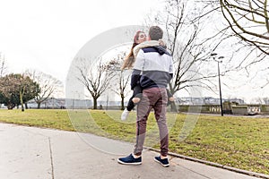 Close up of happy boyfriend holding beloved girlfriend in arms. Cute couple of young people is walking in spring park. Emotion