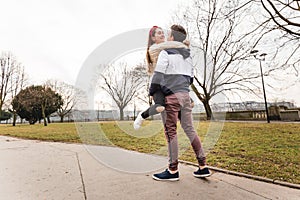 Close up of happy boyfriend holding beloved girlfriend in arms. Cute couple of young people is walking in spring park. Emotion