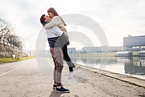 Close up of happy boyfriend holding beloved girlfriend in arms. Cute couple of young people is walking in spring park. Emotion