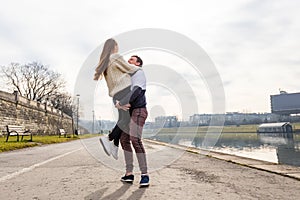 Close up of happy boyfriend holding beloved girlfriend in arms. Cute couple of young people is walking in spring park. Emotion