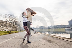 Close up of happy boyfriend holding beloved girlfriend in arms. Cute couple of young people is walking in spring park. Emotion