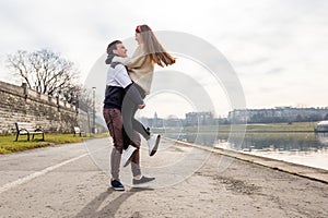 Close up of happy boyfriend holding beloved girlfriend in arms. Cute couple of young people is walking in spring park. Emotion