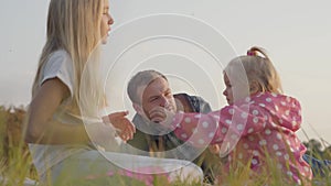 Close-up of happy caucasian family having picnic on the autumn meadow. Pretty blonde daughters dressed in casual clothes