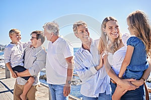 Close up of happy caucasian multi-generation family standing together on seaside promenade on a sunny day. Two little