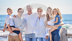 Close up of happy caucasian multi-generation family standing together on seaside promenade on a sunny day. Two little
