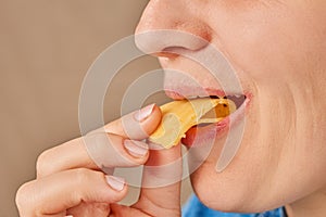 Close-up of a happy Caucasian woman holding a slice of cheese with her hand and biting it. Side view. Low angle view