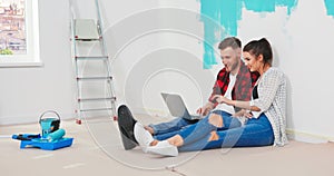 Close up of happy Caucasian young married couple man and woman sitting on the floor