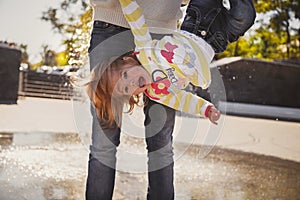 Close up of happy cheerful loving family, young mother is holding small girl upside down