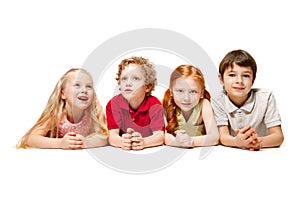 Close-up of happy children lying on floor in studio and looking up, isolated on white background