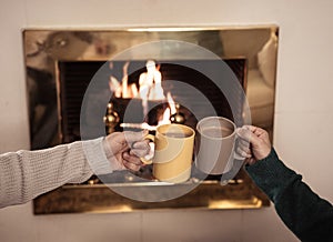 Close up of happy couple drinking hot drink by fire place celebrating love and winter holidays vacation