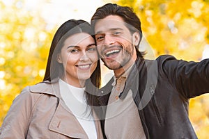 Close up of happy couple taking selfie in autumn forest