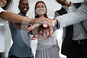 Close up happy diverse business people putting hands together.