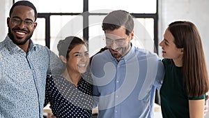 Close up happy diverse employees hugging, celebrating success