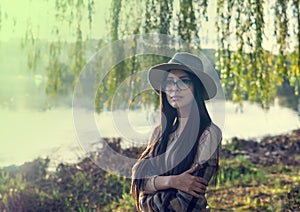 Close up of happy emotionally brunette woman with long hair and hat, smiling at camera