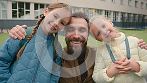 Close up happy family European man two girls kids father parent daughters smiling little sisters primary school joyful