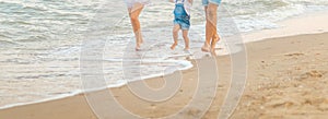 Close up Happy family of three - beatiful wife, father and daughter having fun walking on beach at sunset. Family traveling concep