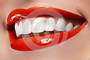 Close-up happy female smile with healthy white teeth, bright red lips make-up. Cosmetology, dentistry and beauty care