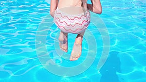 Close up Happy fun loving girl jumping and diving into swimming pool at a pool party in summer sunny day. Slow motion HD