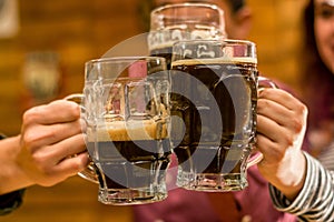 Close up of a happy male friends clinking with beer mugs in pub