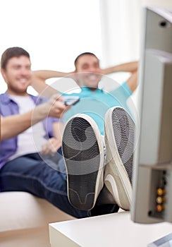 Close up of happy male friends watching tv at home