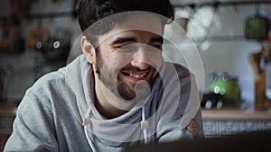 Close up of happy man working on laptop in kitchen at home at night